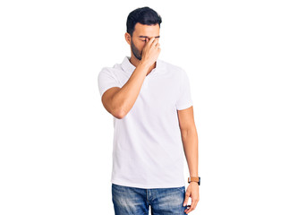Young handsome hispanic man wearing casual clothes tired rubbing nose and eyes feeling fatigue and...