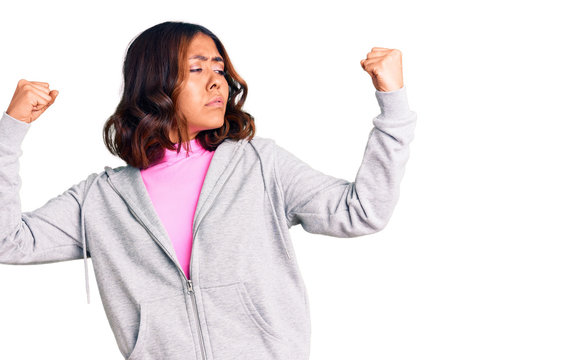 Young beautiful mixed race woman wearing casual sporty clothes showing arms muscles smiling proud. fitness concept.