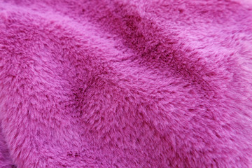 Waves of fluffy pink faux fur, texture of fashionable fur fabric. Small dept of focus.