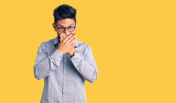 Handsome latin american young man wearing business clothes and glasses shocked covering mouth with hands for mistake. secret concept.