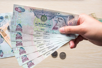 Closeup of a girl's hands holding UAE 500 dirhams currency notes, paper money against a light...