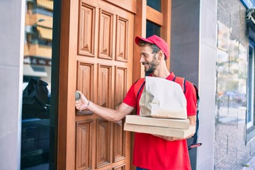 Caucasian delivery man wearing red uniform and delivery backpack smilly happy outdoors holding pizza box