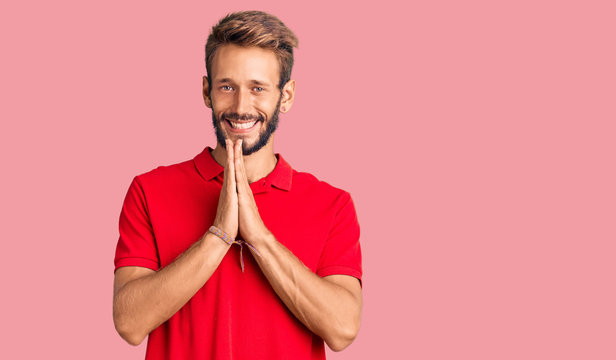 Handsome blond man with beard wearing casual clothes praying with hands together asking for forgiveness smiling confident.