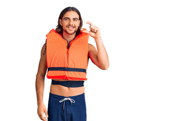 Young handsome man wearing nautical lifejacket smiling and confident gesturing with hand doing...