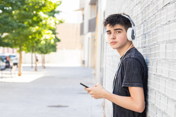 male teenager with headphones and phone on the street