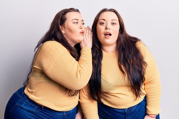 Young plus size twins wearing casual clothes hand on mouth telling secret rumor, whispering malicious talk conversation