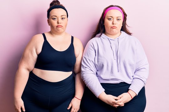 Young plus size twins wearing sportswear depressed and worry for distress, crying angry and afraid. sad expression.