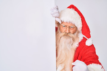 Old senior man with grey hair and long beard wearing santa claus costume holding banner annoyed and frustrated shouting with anger, yelling crazy with anger and hand raised