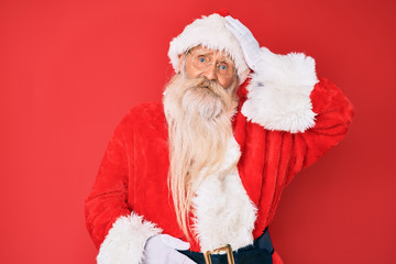Old senior man with grey hair and long beard wearing traditional santa claus costume confuse and wonder about question. uncertain with doubt, thinking with hand on head. pensive concept.