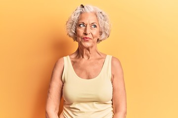 Senior grey-haired woman wearing casual clothes smiling looking to the side and staring away thinking.