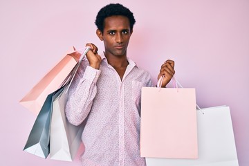 African handsome man holding shopping bags skeptic and nervous, frowning upset because of problem....