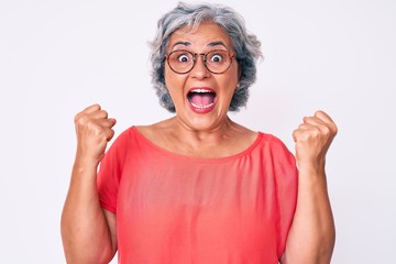 Senior hispanic grey- haired woman wearing casual clothes and glasses celebrating surprised and amazed for success with arms raised and open eyes. winner concept.