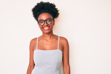 Young african american woman wearing casual clothes and glasses looking positive and happy standing and smiling with a confident smile showing teeth