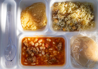 Turkish wedding and circumcision ceremony dinner in coronavirus pandemic days. Beans with meat, rice with meat, halvah and bread. Serving as table d'hote.