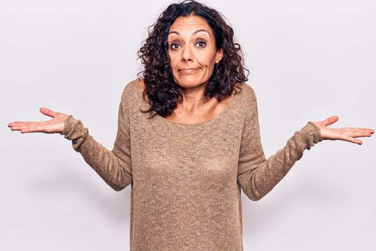 Middle age beautiful woman wearing casual sweater clueless and confused with open arms, no idea and doubtful face.
