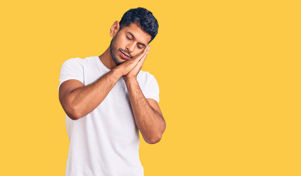 Young latin man wearing casual clothes sleeping tired dreaming and posing with hands together while smiling with closed eyes.