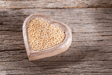 organic quinoa grains in bowl on wood