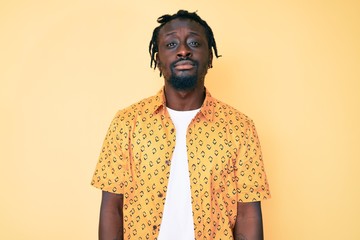Young african american man with braids wearing casual clothes relaxed with serious expression on...
