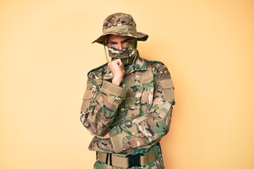 Young handsome man wearing camouflage army uniform and balaclava thinking looking tired and bored with depression problems with crossed arms.