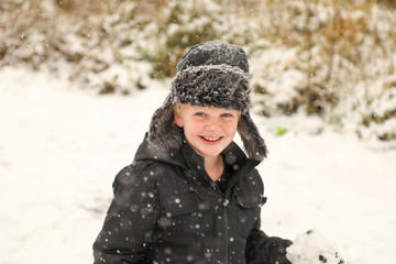 Boy playing in fresh snow smiling at camera during snow storm in New South Wales, Australia