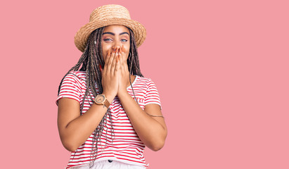 Young african american woman with braids wearing summer hat laughing and embarrassed giggle...