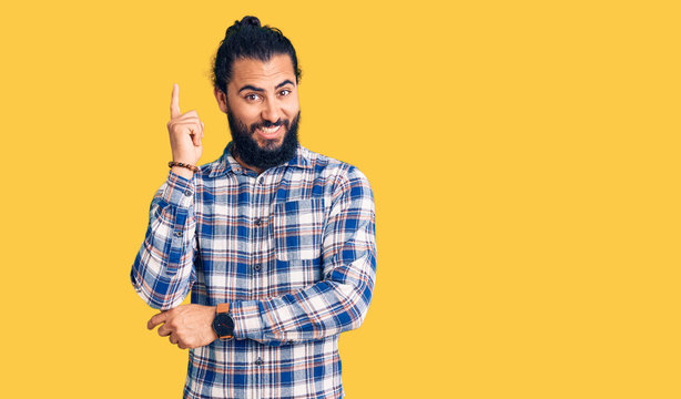 Young arab man wearing casual clothes with a big smile on face, pointing with hand and finger to the side looking at the camera.