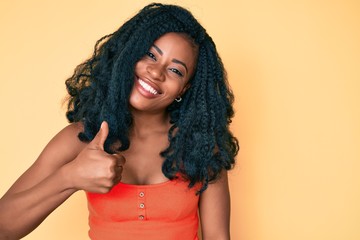 Beautiful african woman wearing casual clothes doing happy thumbs up gesture with hand. approving expression looking at the camera showing success.