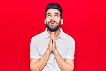 Young handsome man with beard wearing casual polo begging and praying with hands together with hope expression on face very emotional and worried. begging.