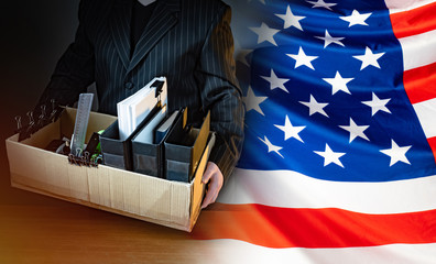 Unemployed. Man holds a box with personal belongings. USA flag. Concept - unemployed American. American was fired. USA resident is unemployed. Stationery in a cardboard box. American labor market