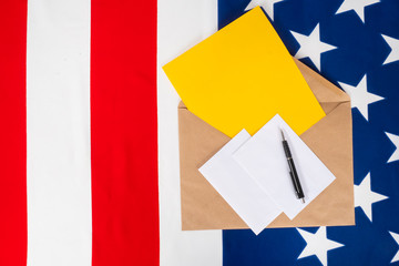 Voting by mail in USA. Envelope with electoral bill and pen. Craft envelope on background of USA flag. Concept - presidential elections in United States. Voting in elections by mail. US Remote Voting
