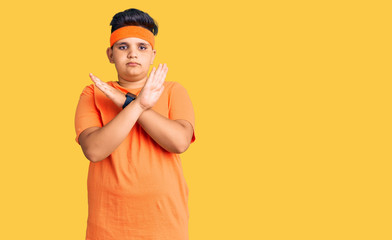 Little boy kid wearing sportswear rejection expression crossing arms doing negative sign, angry face