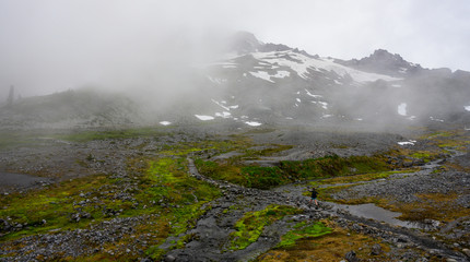 Woman Rock Hops on Trail below Foggy Mount Rainier