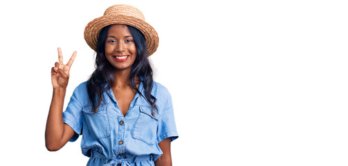 Young indian girl wearing summer hat showing and pointing up with fingers number two while smiling...