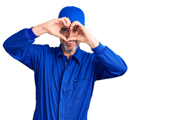 Naklejka premium Middle age handsome man wearing mechanic uniform doing heart shape with hand and fingers smiling looking through sign