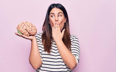 Young beautiful brunette woman asking for memory healthy and mental care holding brain covering...