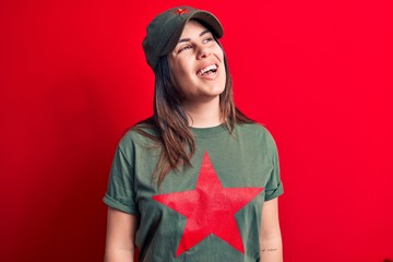 Young beautiful brunette woman wearing cap and t-shirt with red star communist symbol looking to...