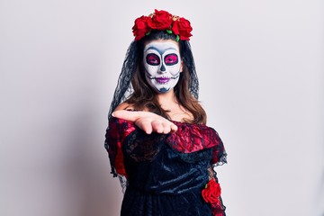 Young woman wearing day of the dead costume over white smiling cheerful offering palm hand giving assistance and acceptance.