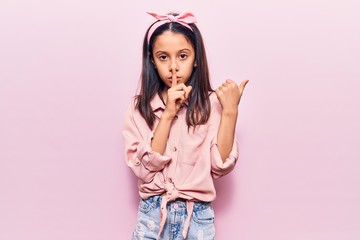 Beautiful child girl wearing casual clothes asking to be quiet with finger on lips pointing with hand to the side. silence and secret concept.