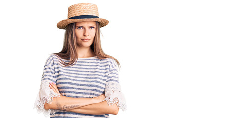 Beautiful caucasian woman wearing summer hat skeptic and nervous, disapproving expression on face with crossed arms. negative person.