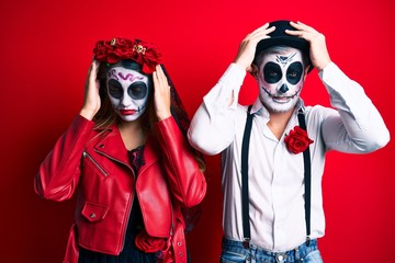 Couple wearing day of the dead costume over red suffering from headache desperate and stressed...