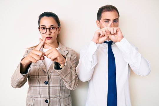 Beautiful couple wearing business clothes rejection expression crossing fingers doing negative sign