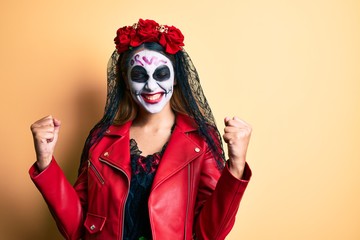Woman wearing day of the dead costume over yellow very happy and excited doing winner gesture with arms raised, smiling and screaming for success. celebration concept.
