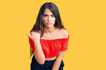 Brunette teenager girl wearing casual clothes angry and mad raising fist frustrated and furious while shouting with anger. rage and aggressive concept.