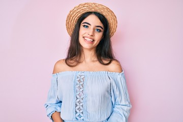 Brunette teenager girl wearing summer hat looking positive and happy standing and smiling with a confident smile showing teeth