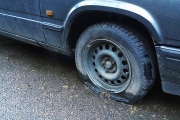 old car with flat tyre on the street, closeup