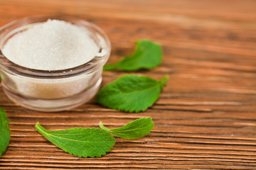 Stevia leaves with sugar in a glass bowl on a wooden background. Selective focus.
