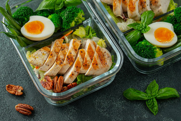 Healthy meal prep containers with green beans, chicken breast and broccoli. A set of food for keto diet in lunchbox on a dark concrete background. Top view