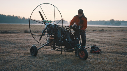 Tandem paramotorgliding. Man in standing near the paramotor during the sunset. High quality photo