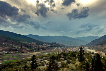 Obraz premium Landscape with mountains and clouds. Serine view of Paro Valley, Paro River, Mountain Ranges, and paddy fields of Paro, Bhutan.