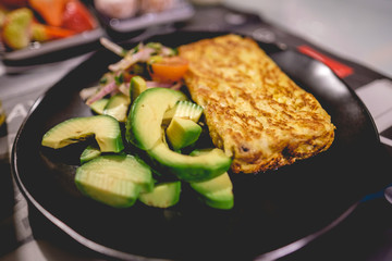 Back plate with fresh avocado, sauteed omelette and salad of cherry tomato, onion and coriander
